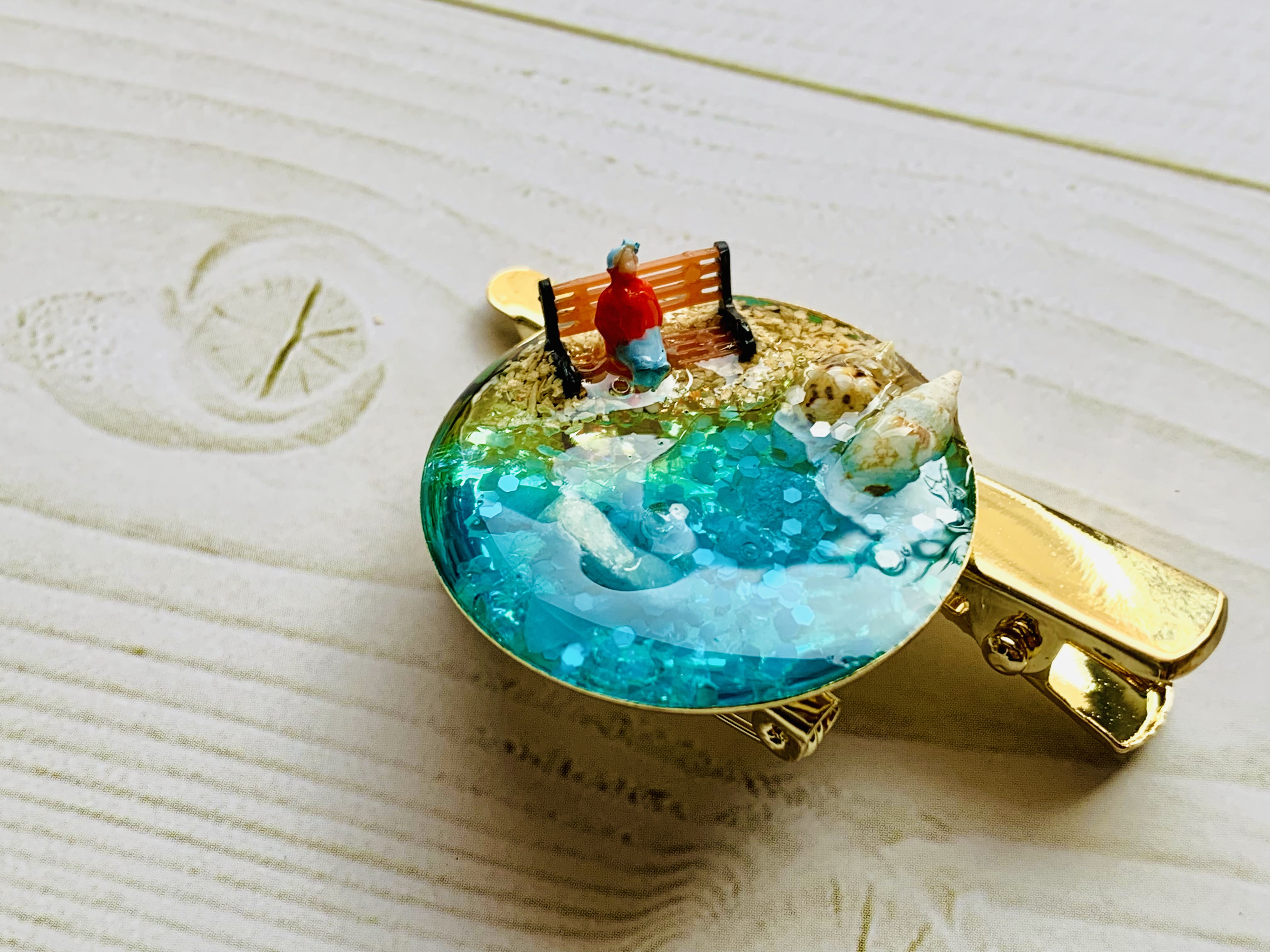 海とベンチに座る女性のブローチ